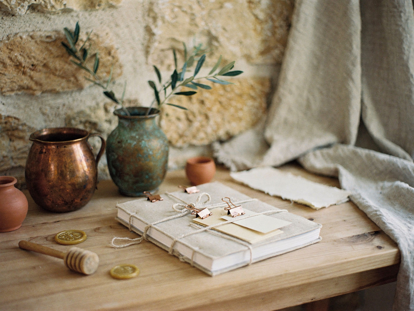 Twine, copper clips, and index cards gathered into a single folio on a wooden table.